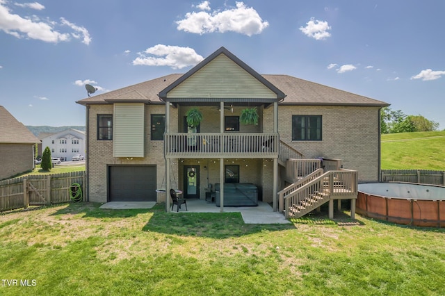 back of house with a fenced backyard, a lawn, a hot tub, and brick siding