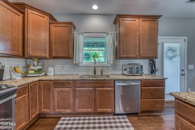 kitchen with a sink, appliances with stainless steel finishes, tasteful backsplash, and dark wood finished floors