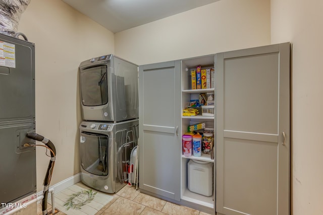 clothes washing area featuring baseboards, light tile patterned floors, laundry area, and stacked washer / dryer