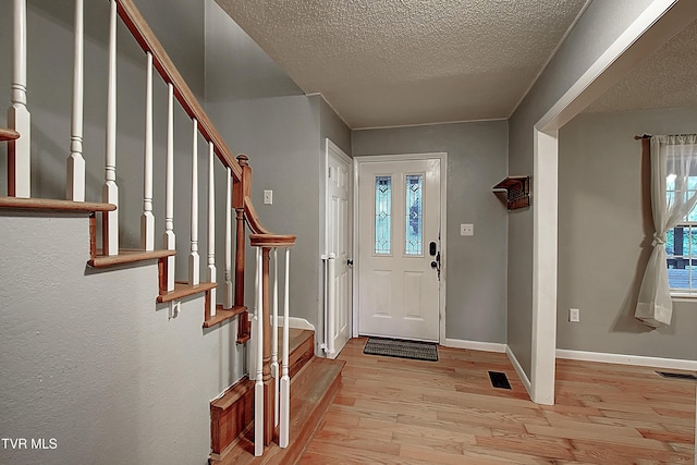 foyer with baseboards, visible vents, stairway, and light wood-type flooring
