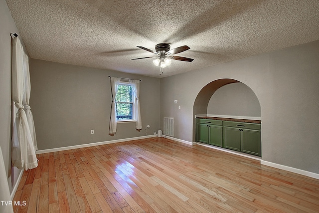 empty room featuring baseboards, ceiling fan, light wood finished floors, and visible vents