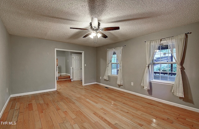 spare room featuring baseboards, a ceiling fan, and light wood finished floors