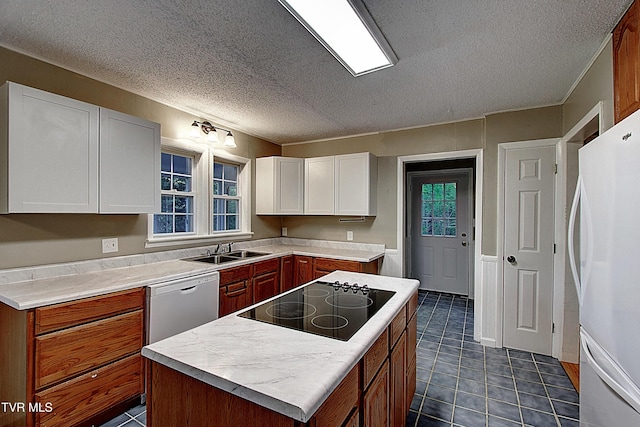 kitchen with a textured ceiling, a center island, a sink, white cabinets, and white appliances