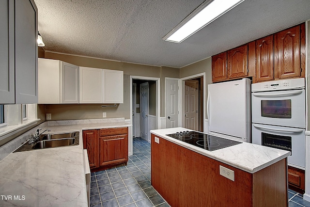 kitchen featuring white appliances, a center island, a textured ceiling, tile patterned floors, and a sink