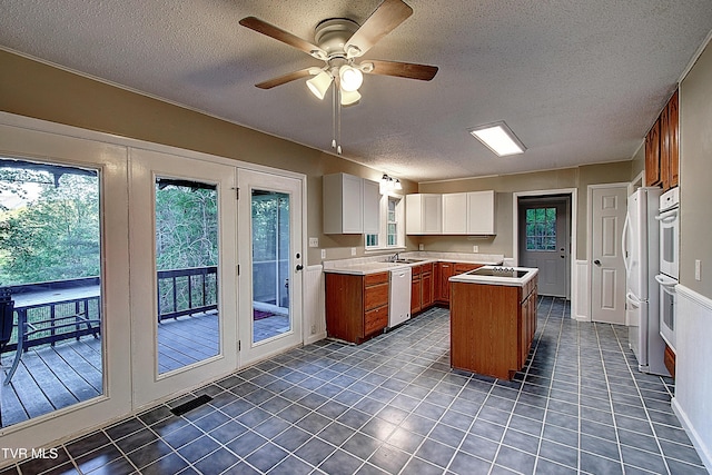 kitchen featuring white appliances, a textured ceiling, a sink, and light countertops