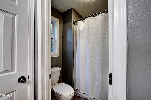 bathroom featuring a textured ceiling, a shower with shower curtain, and toilet
