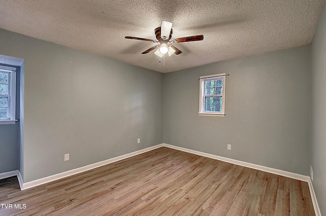 empty room with a textured ceiling, ceiling fan, baseboards, and wood finished floors