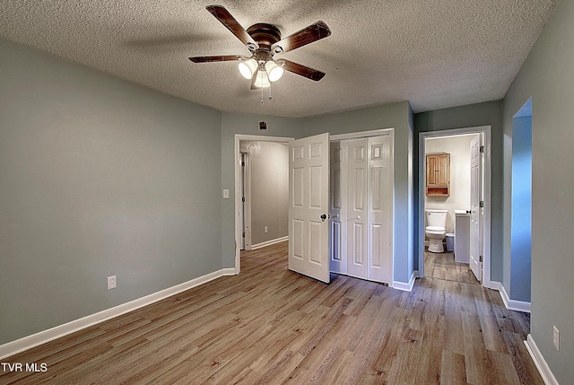 unfurnished bedroom featuring a closet, wood finished floors, baseboards, connected bathroom, and a textured ceiling
