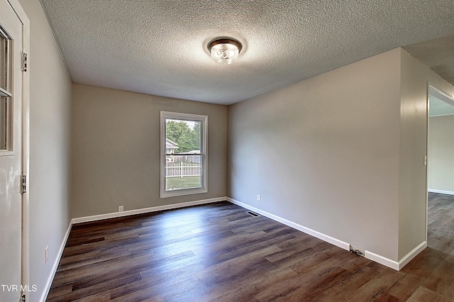 unfurnished room featuring dark wood-style floors, a textured ceiling, and baseboards