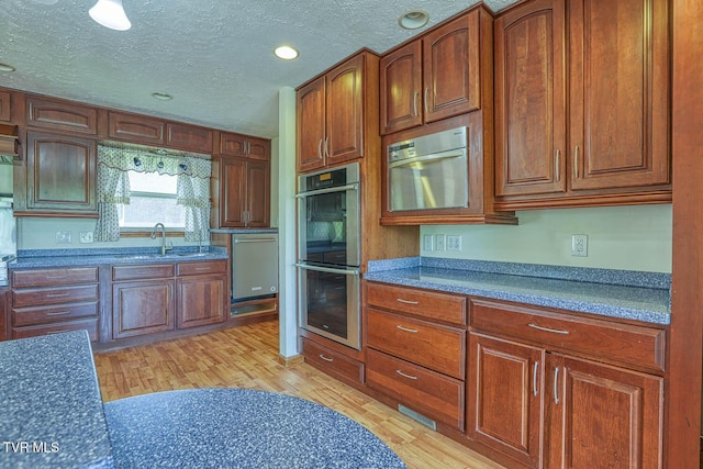 2653 Suffolk St, Kingsport, TN 37660 - kitchen with appliances with stainless steel finishes, a sink, light wood finished floors, a textured ceiling, and brown cabinetry