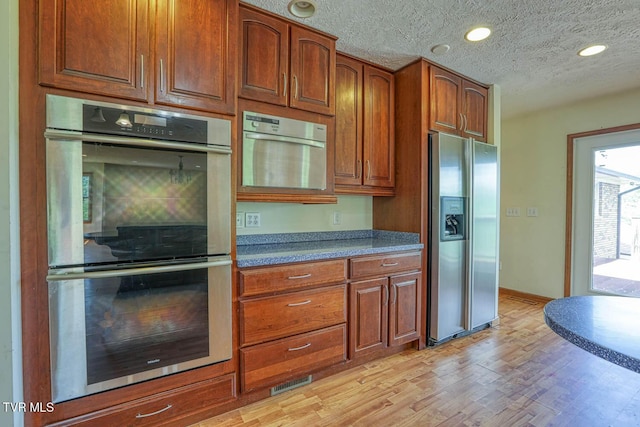 2653 Suffolk St, Kingsport, TN 37660 - kitchen featuring stainless steel appliances, light wood-style floors, brown cabinets, a textured ceiling, and baseboards