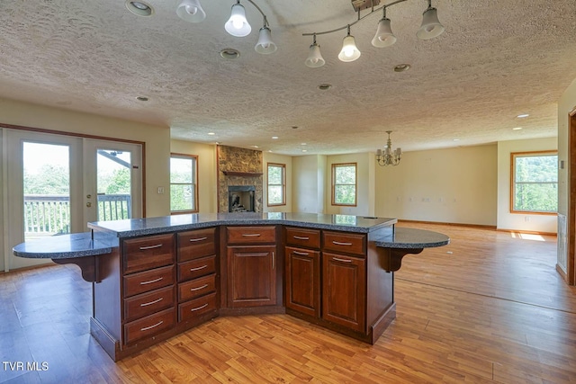 2653 Suffolk St, Kingsport, TN 37660 - kitchen featuring open floor plan, a breakfast bar, light wood finished floors, a textured ceiling, and a stone fireplace