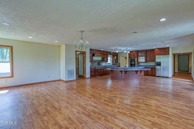 2653 Suffolk St, Kingsport, TN 37660 - kitchen featuring appliances with stainless steel finishes, a textured ceiling, light wood-type flooring, a kitchen bar, and open floor plan