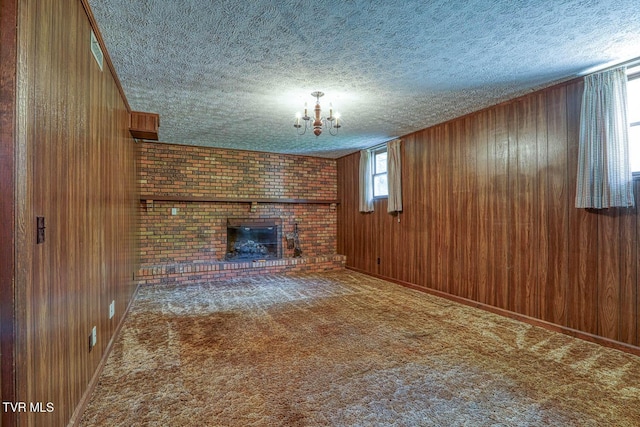 2653 Suffolk St, Kingsport, TN 37660 - unfurnished living room with a textured ceiling, wooden walls, a fireplace, a chandelier, and baseboards