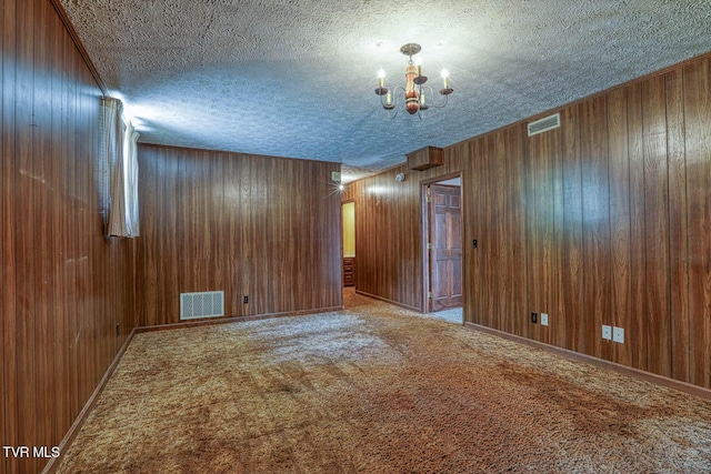 2653 Suffolk St, Kingsport, TN 37660 - empty room with a textured ceiling, a chandelier, carpet floors, and wood walls