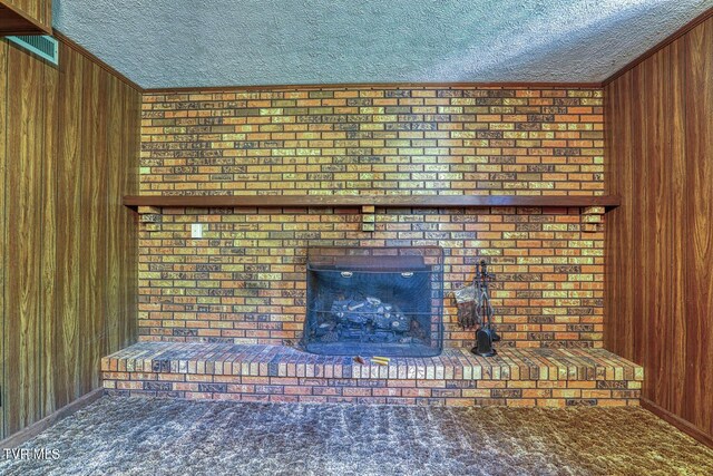 2653 Suffolk St, Kingsport, TN 37660 - unfurnished living room with a textured ceiling, wood walls, carpet flooring, a brick fireplace, and crown molding