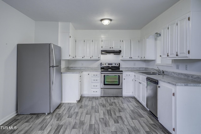 kitchen featuring appliances with stainless steel finishes, a sink, under cabinet range hood, and white cabinetry