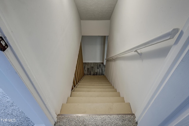 staircase featuring a textured ceiling