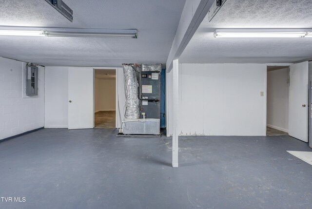 finished below grade area with electric panel, a textured ceiling, and heating unit