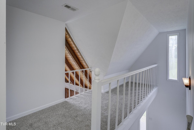 stairway featuring lofted ceiling, carpet, and baseboards