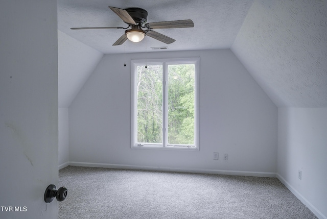 bonus room with a textured ceiling, lofted ceiling, a ceiling fan, carpet flooring, and baseboards