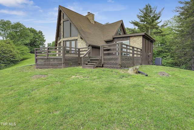 back of house featuring stone siding, a deck, and a lawn