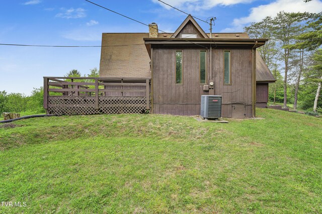 back of property with central AC, a yard, a chimney, and a deck