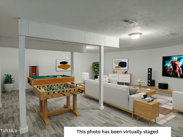 playroom featuring light wood-style flooring, billiards table, and a textured ceiling