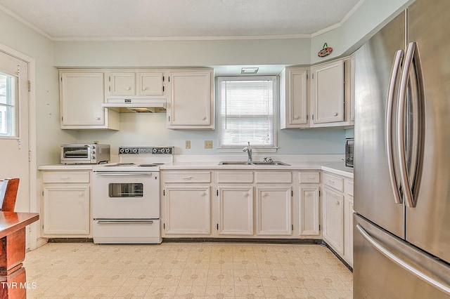 kitchen with electric range, a sink, freestanding refrigerator, under cabinet range hood, and a wealth of natural light