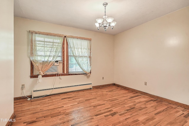 unfurnished room featuring baseboards, a notable chandelier, a baseboard heating unit, and wood finished floors