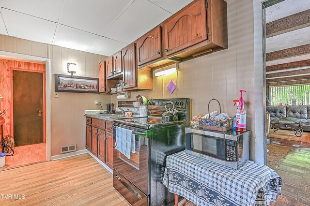 3851 Helen Henderson Hwy, Davenport, VA 24239 - kitchen with brown cabinetry, black electric range oven, stainless steel microwave, light wood-type flooring, and visible vents