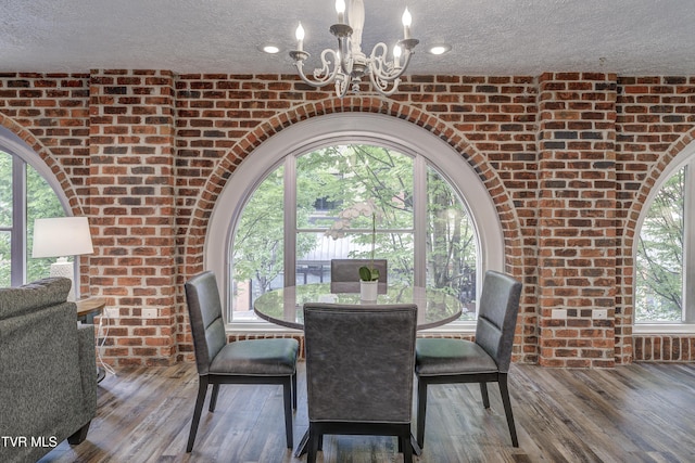 200 E Main St Unit 201, Johnson City, TN 37604 - dining area with brick wall, a chandelier, a textured ceiling, wood finished floors, and healthy amount of natural light