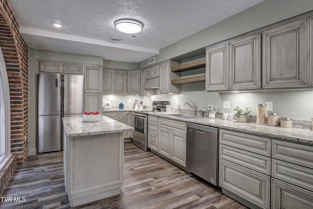 200 E Main St Unit 201, Johnson City, TN 37604 - kitchen featuring appliances with stainless steel finishes, a textured ceiling, dark wood-style floors, a center island, and light stone counters