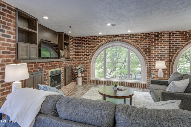 200 E Main St Unit 201, Johnson City, TN 37604 - living room featuring a textured ceiling, brick wall, a brick fireplace, light wood-style floors, and recessed lighting