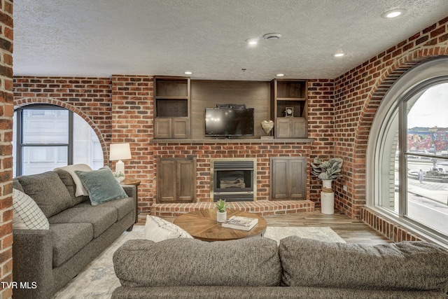 200 E Main St Unit 201, Johnson City, TN 37604 - living room featuring a textured ceiling, light wood-style flooring, brick wall, a fireplace, and recessed lighting