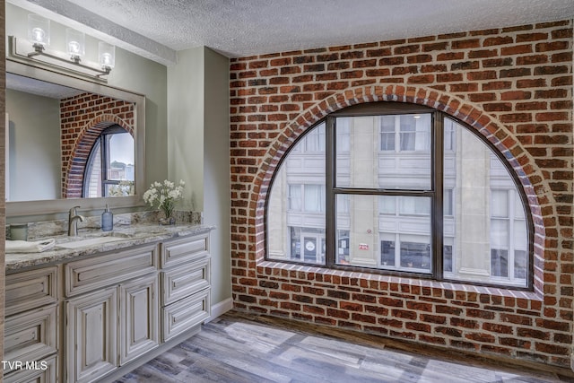 200 E Main St Unit 201, Johnson City, TN 37604 - bathroom featuring wood finished floors, vanity, a textured ceiling, and brick wall