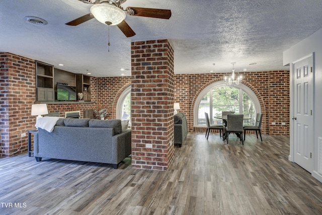 200 E Main St Unit 201, Johnson City, TN 37604 - living room with a fireplace, a textured ceiling, brick wall, wood finished floors, and a chandelier