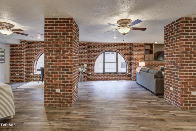 200 E Main St Unit 201, Johnson City, TN 37604 - unfurnished living room featuring a ceiling fan, a textured ceiling, hardwood / wood-style flooring, and brick wall