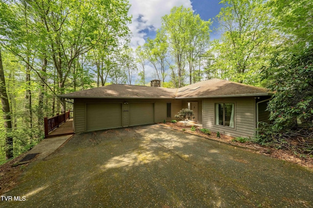view of front of home featuring a chimney, an attached garage, and driveway
