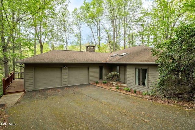 ranch-style house with an attached garage, a shingled roof, aphalt driveway, and a chimney