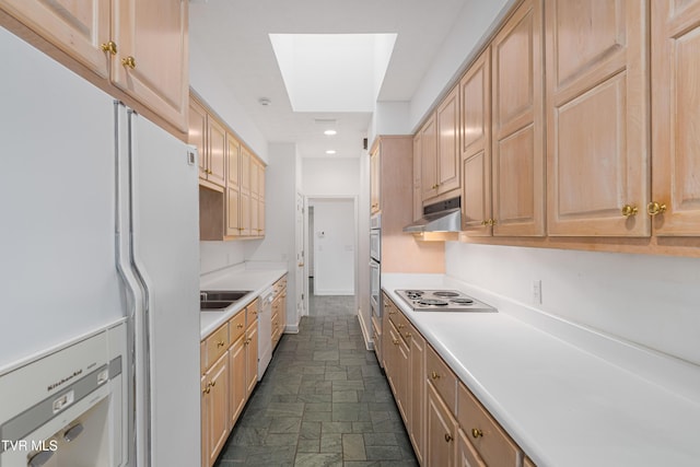 kitchen featuring appliances with stainless steel finishes, light countertops, light brown cabinets, under cabinet range hood, and stone tile floors