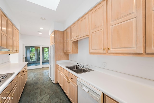 kitchen featuring a sink, light brown cabinets, white appliances, light countertops, and stone finish floor