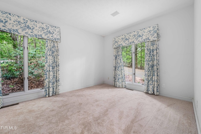 carpeted spare room featuring baseboards and visible vents