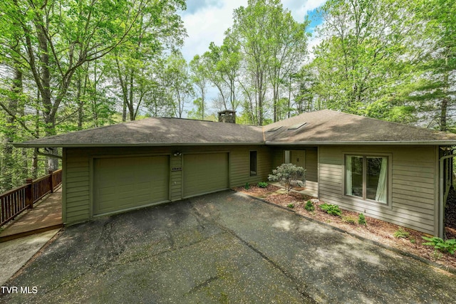 view of front of home with a garage, aphalt driveway, roof with shingles, and a chimney