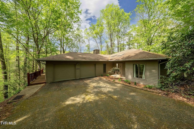 view of front of property featuring driveway, a chimney, and a garage