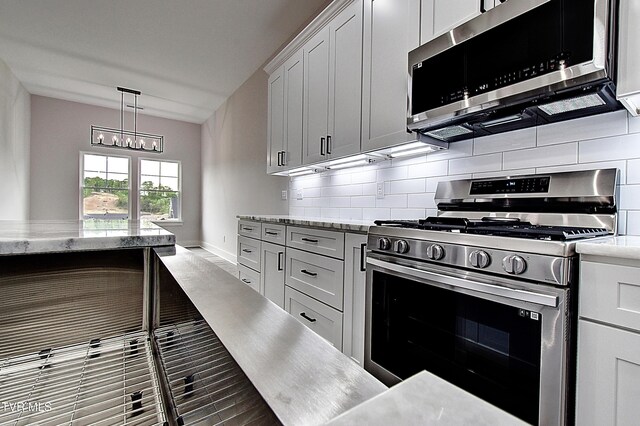 kitchen with pendant lighting, appliances with stainless steel finishes, a chandelier, and tasteful backsplash
