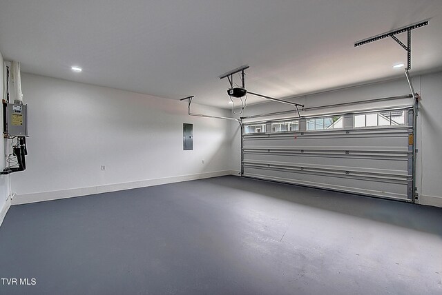 garage featuring baseboards, a garage door opener, electric panel, and recessed lighting