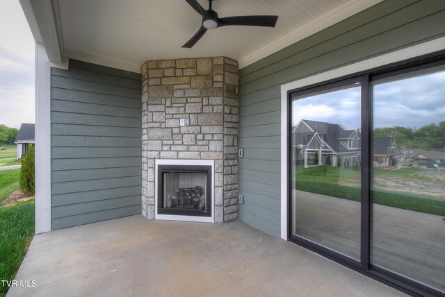 unfurnished living room featuring wood walls, ceiling fan, a wealth of natural light, and an outdoor stone fireplace