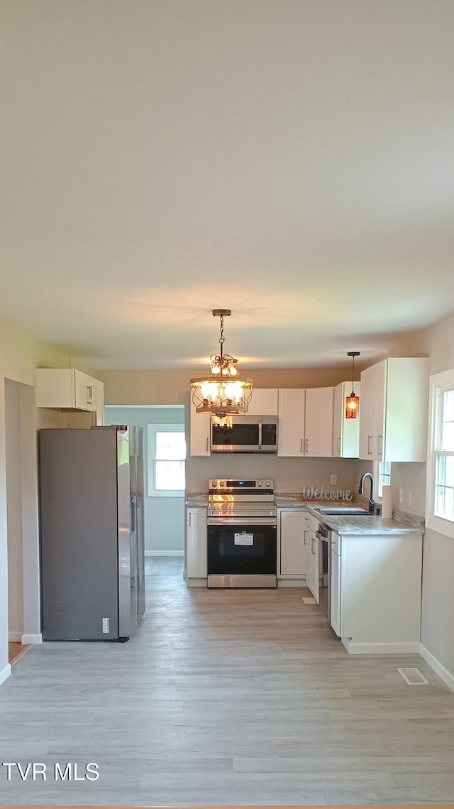 2160 Whirlwind Rd, Greeneville, TN 37743 - kitchen with stainless steel appliances, baseboards, decorative light fixtures, light countertops, and light wood-style floors
