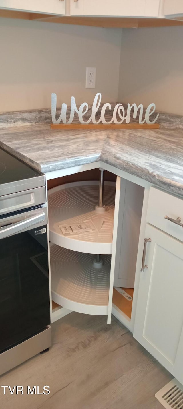 2160 Whirlwind Rd, Greeneville, TN 37743 - room details with white cabinets, light countertops, wood finished floors, and stainless steel electric stove